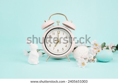 Cute easter bunny or rabbit with an alarm clock, eggs and cherry blossoms, spring holiday, greeting card 