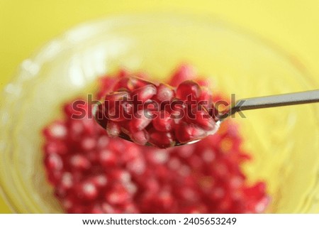 a cup of pomegranate seeds with yellow background