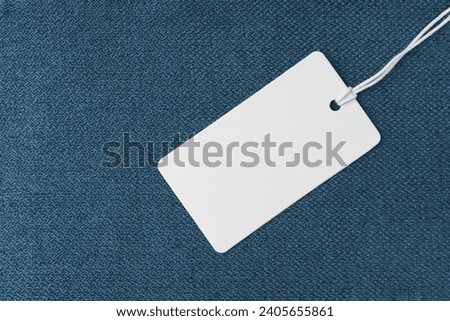 Textile background, blue coarse fabric texture with white empty clothing tag, jacquard woven upholstery, furniture textile material, backdrop, mockup. Cloth structure close up.