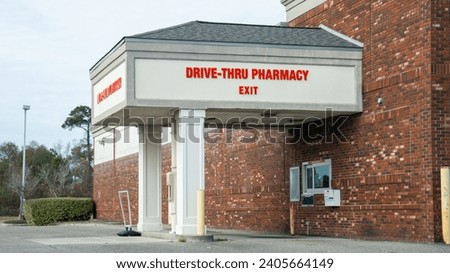 Drive-thru pharmacy exit with red signage on a brick building, covered drive-up window, and a clear day.