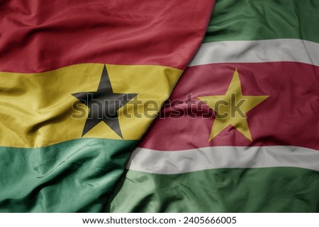 big waving national colorful flag of suriname and national flag of ghana . macro