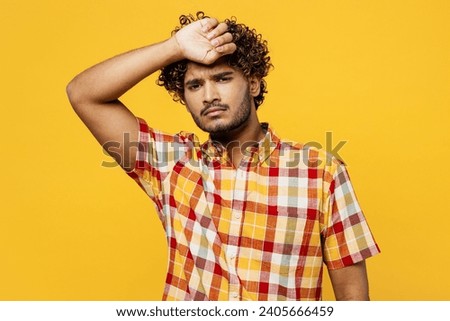 Young sick ill tired sad Indian man he wearing shirt casual clothes look camera put hand on forehead suffer from headache isolated on plain yellow color background studio portrait. Lifestyle concept