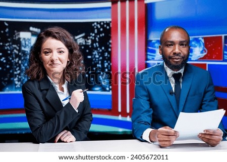 Journalists team reporting live news in newsroom, working to deliver latest information for international content. Diverse broadcasters covering all topics and global scandal events. Royalty-Free Stock Photo #2405672011