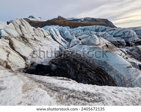 Frost covered Vatnajokull iceberg in Iceland with incredibly large glaciers painted white and blue. Arctic hills covered in snow and frozen icy cold water compose an icelandic picture.
