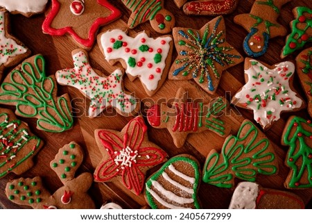 Top view of colorful red-white-green home decorated gingerbread cookies for Christmas on a wooden board. Holiday tradition of cookie decorating