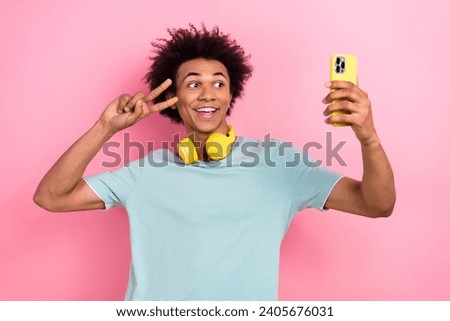 Photo of funky excited guy wear blue t-shirt headphones v-sing cover eye recording video vlog device isolated pink color background