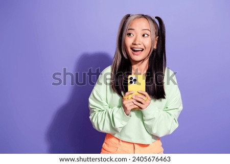 Photo of excited youngster chinese blogger girl hold phone during her weekend abroad look empty space isolated on violet color background