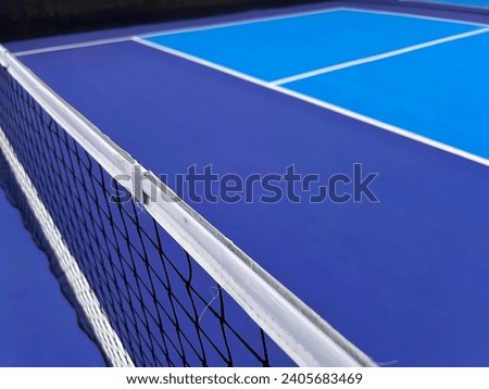 Pickle ball court in blue and white colors with net in black and white. Wide view of a pickleball court Royalty-Free Stock Photo #2405683469