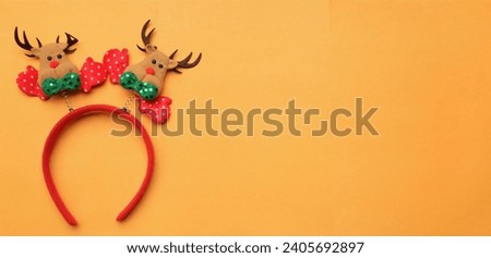 cute Christmas headbands with christmas reindeer horns isolate on a orange backdrop. concept of joyful Christmas party,New year is coming soon, festive season decoration with Christmas elements