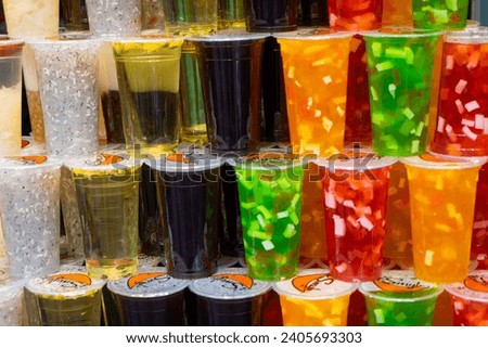 A vibrant collection of various drinks and juices, displayed in clear cups, showcasing a mix of colors and textures at a market in Wuchang , China.