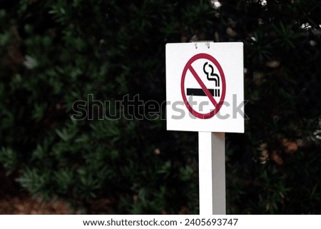 No smoking sign outdoor in a forest on a white plywood wooden stand. 