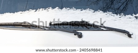 Snow accumulated on the windshield wiper of a parked car.