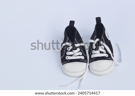 Baby's little black sneakers on a white background. The concept of waiting for a baby and the concept of traveling with baby, children's lifestyle