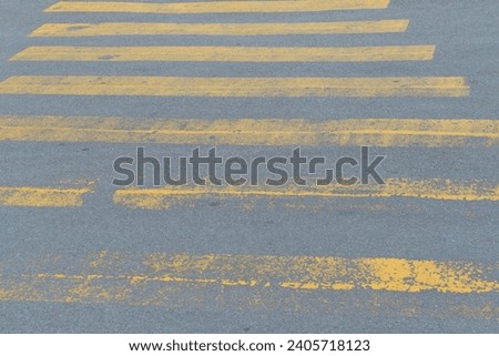 It is the aged yellow pedestrian crossing. This is a weathered zebra crossing. It is a close up view of an yellow safety walkway.