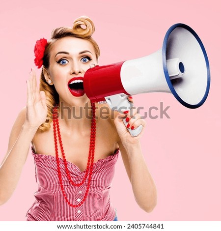 Blonde haired woman holding mega phone megaphone loudspeaker, shout something. Girl in red pin up style clothing, rose pink colour. Female model in retro vintage studio concept. Square photo Royalty-Free Stock Photo #2405744841