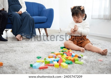 child girl playing with colorful toy blocks on the carpet floor