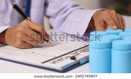 Close-up of a female doctor's hand signing a medical document on a clipboard. and recommending certain medicines to patients on a laptop