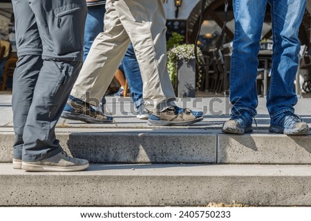 Legs of a group of men standing too close together Royalty-Free Stock Photo #2405750233
