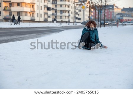 The amused young woman fell on the snow. Royalty-Free Stock Photo #2405765015