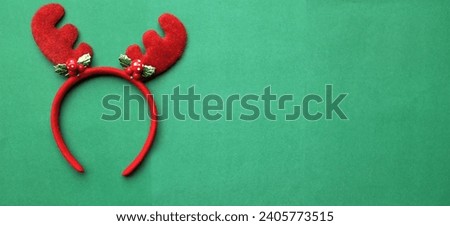 cute christmas headbands with funny red deer horns isolate on a green backdrop. concept of joyful christmas party,new year is coming soon, festive season decoration with christmas elements