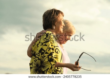 An affectionate clasp between elders, a shared smile radiant; the golden years celebrated with a loving hug. Royalty-Free Stock Photo #2405778235
