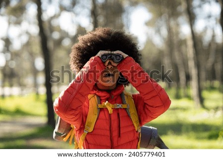 young african american woman trekking looking with binoculars in the mountain
