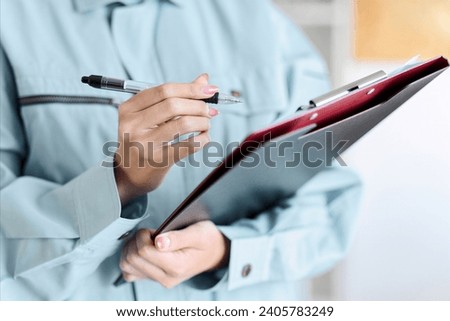 A professional woman comes to your home wearing work clothes to conduct an assessment. Royalty-Free Stock Photo #2405783249