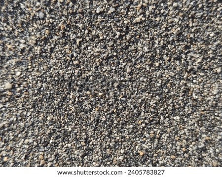 the texture of the grayish-black beach sand is very visible the details of each sand in the picture. 
