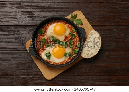 Delicious shakshuka in frying pan on wooden table, top view Royalty-Free Stock Photo #2405793747