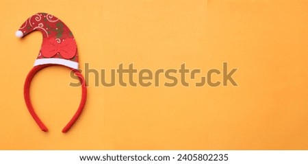 cute Christmas headbands with christmas 
red santa claus hat isolate on a orange backdrop. concept of joyful Christmas party,New year is coming soon, festive season decoration with Christmas elements