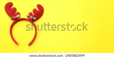 cute christmas headbands with funny red deer horns isolate on a yellow  backdrop. concept of joyful christmas party,new year is coming soon, festive season decoration with christmas elements