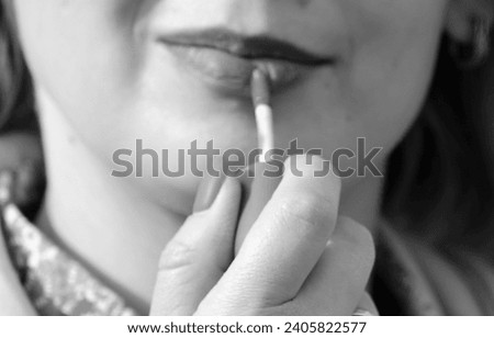 The process of applying lipstick to women's lips. Black and white photo.