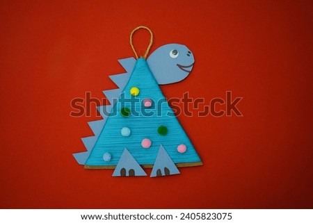 Christmas tree toy a dragon made by a child out of cardboard and blue threads lies on a red background. The symbol of 2024. Educational and craft activity.