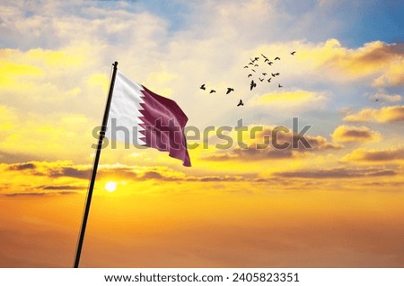 Waving flag of Qatar against the background of a sunset or sunrise. Qatar flag for Independence Day. The symbol of the state on wavy fabric.