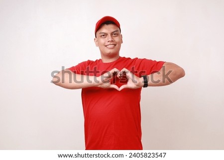 Handsome young asian courier standing while making love shape with his hands against white background
