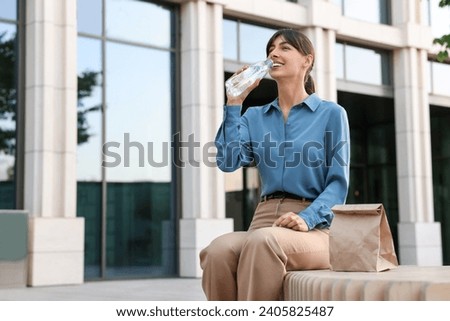 Lunch time. Businesswoman drinking water from bottle on bench outdoors