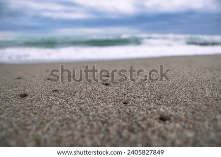 Close up sea sand beach with foam and waves photo. Sand beach surface with selective focus. Mediterranean sea, nautical background. 