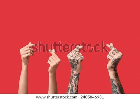 Woman and man making heart with fingers on red background