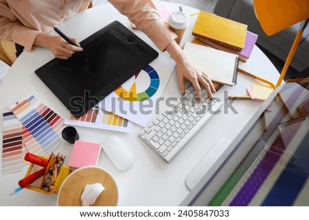 Female graphic designer working with tablet at table in office, closeup Royalty-Free Stock Photo #2405847033