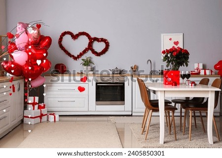 Interior of light kitchen with heart-shaped balloons and bouquet of roses on dining table. Valentine's Day celebration