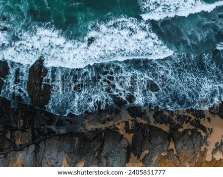 Aerial view of the huge Pacific ocean waves hitting the shore of California.