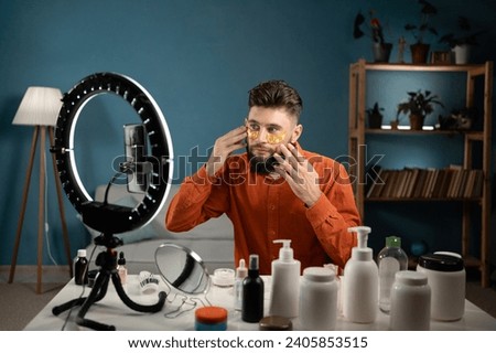 Bearded man beauty vlogger. Video by smartphone sharing on social media. Male blogger make-up artist or cosmetologist live. Recording skin care routine tutorial. Copy space