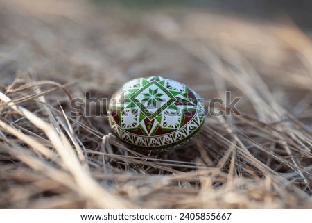 Traditional Ukrainian Easter egg in green-brown colors on a background of hay Royalty-Free Stock Photo #2405855667