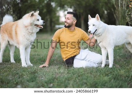 young adult sitting on the floor resting with his dogs after training them