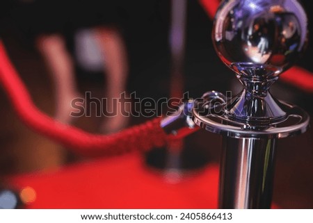 Red carpet with ropes and golden barriers on a luxury party entrance, cinema premiere film festival event award gala ceremony, wealthy rich guests arriving, outdoor decoration elements, summer day Royalty-Free Stock Photo #2405866413