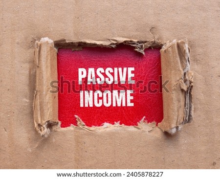 Passive income lettering on ripped cardboard paper with red background. Business concept photo.