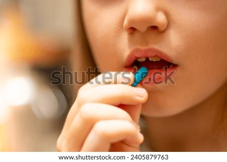 the girl holding a pill near her mouth Royalty-Free Stock Photo #2405879763