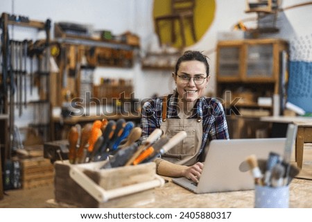 Young craftswoman using laptop in her workshop
