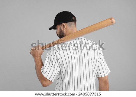 Man in stylish black baseball cap holding bat on light grey background, back view