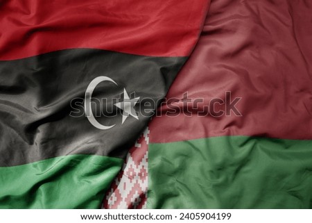 big waving national colorful flag of belarus and national flag of libya . macro